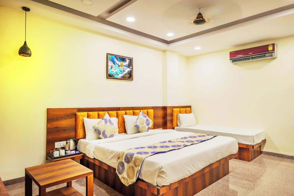A hotel room with a wooden bed, bedside tables, a ceiling fan, an air conditioner, and a framed picture on the wall.