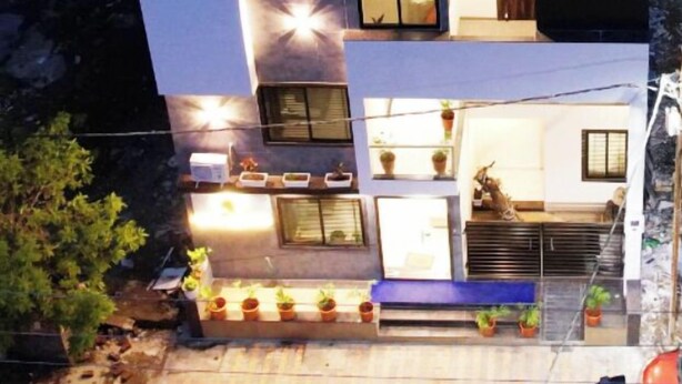 A multi-story modern building with large windows and a flat roof. - Hotel Dream Inn (Sanwer)