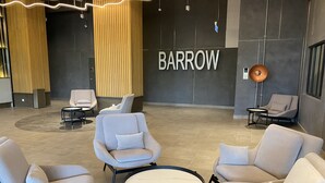 Een moderne lobby met een 'BARROW' bord, comfortabele zitplaatsen en een opvallend lichtontwerp voor het plafond.
