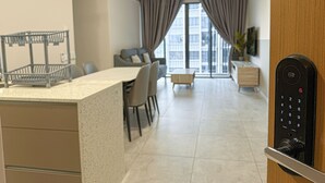 Een moderne keuken met een vast kookeiland, een eethoek met stoelen, een bank en een uitzicht op de stad door grote ramen.