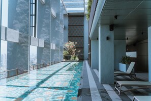 A modern indoor pool area with a patterned floor, large windows, and a seating area with a potted plant. - Millerz Square By Just Stay (Kuala Lumpur)
