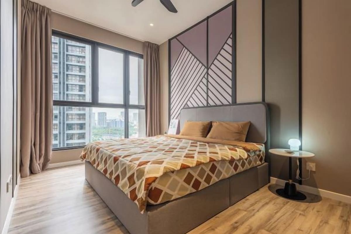 Um quarto moderno com uma cama grande, vista de prédios pela janela e um design geométrico na parede.