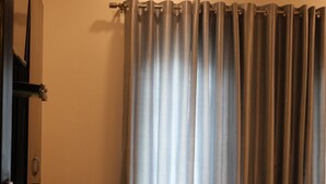 A bedroom with a bed, a chair, and a curtain.