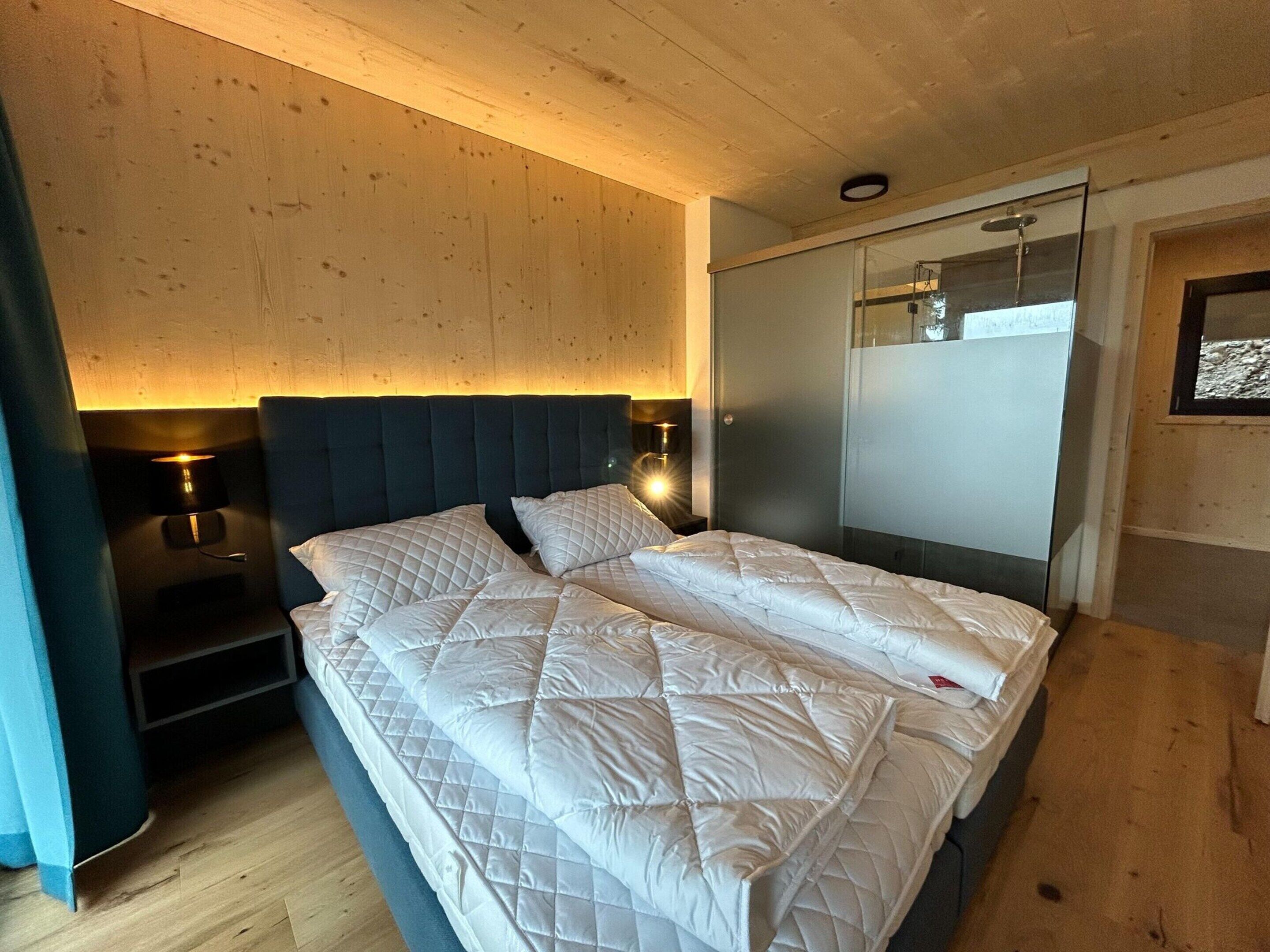 Une chambre à coucher comprenant un lit, deux tables de chevet, une armoire et un luminaire fixé au mur.