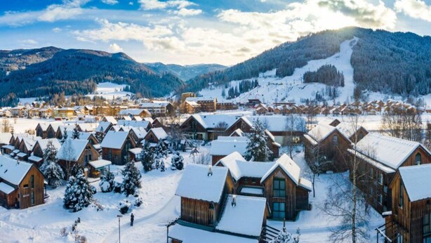 A snow-covered village with wooden cabins, a ski slope, and mountains in the background. - Traditional Chalet With Terrace (Sankt Georgen am Kreischberg)