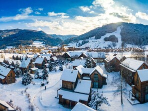 A snow-covered village with wooden cabins, a ski slope, and mountains in the background. - Traditional Chalet With Terrace (Sankt Georgen am Kreischberg)