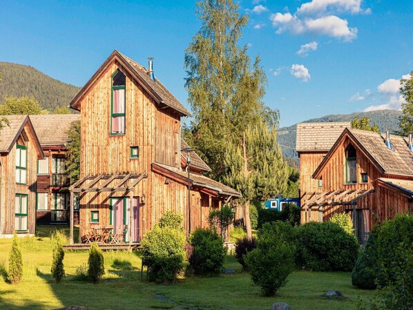 A wooden cabin with a steep roof, a chimney, and a small porch with chairs. - Traditional Chalet With Terrace (Sankt Georgen am Kreischberg)