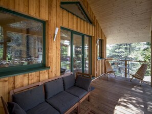 Eine Holzhütte mit einer Terrasse, einem Sofa und einem Sessel.