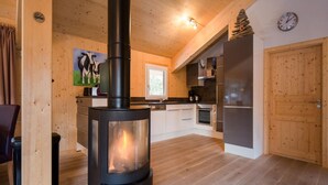 A modern kitchen with a wood-burning stove, wooden cabinets, and a large window. - Chalet in Austria Near Ski Slopes & Sauna (Stadl-Predlitz)