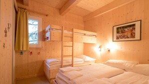 A cozy wooden cabin room with bunk beds, a window with a view of snow-covered trees, and a framed picture on the wall. - Chalet in Austria Near Ski Slopes & Sauna (Stadl-Predlitz)
