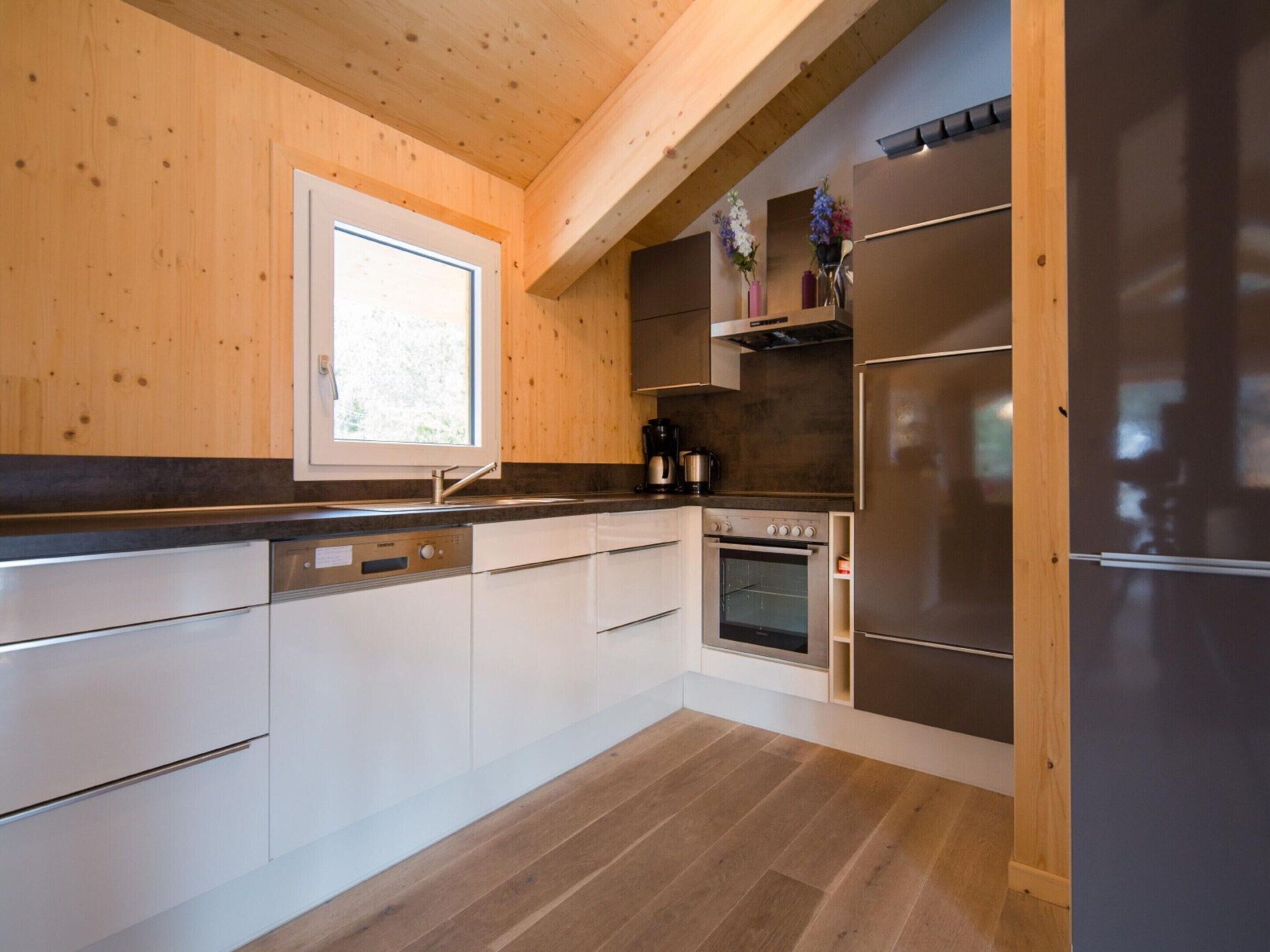 Eine moderne Küche mit Holzwänden, einem eingebauten Ofen und einem Edelstahl-Kühlschrank.