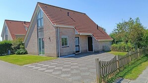 A two-story house with a red-tiled roof, a front porch, and a fenced yard. - Bungalow Near Breskens Beach and Lighthouse (Breskens)