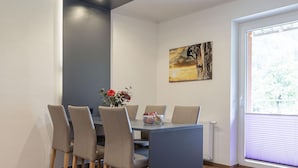 A dining area with a table and chairs, a vase with flowers, and a painting on the wall. - Modern Apartment With Balcony (Eisenerz)