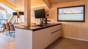 Une cuisine moderne avec des murs en bois, une grande fenêtre et un coin repas avec des chaises.