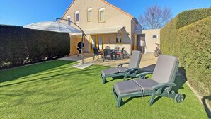 A house with a patio, outdoor seating, and a well-maintained lawn. - Bungalow in Breskens Near the Beach (Breskens)