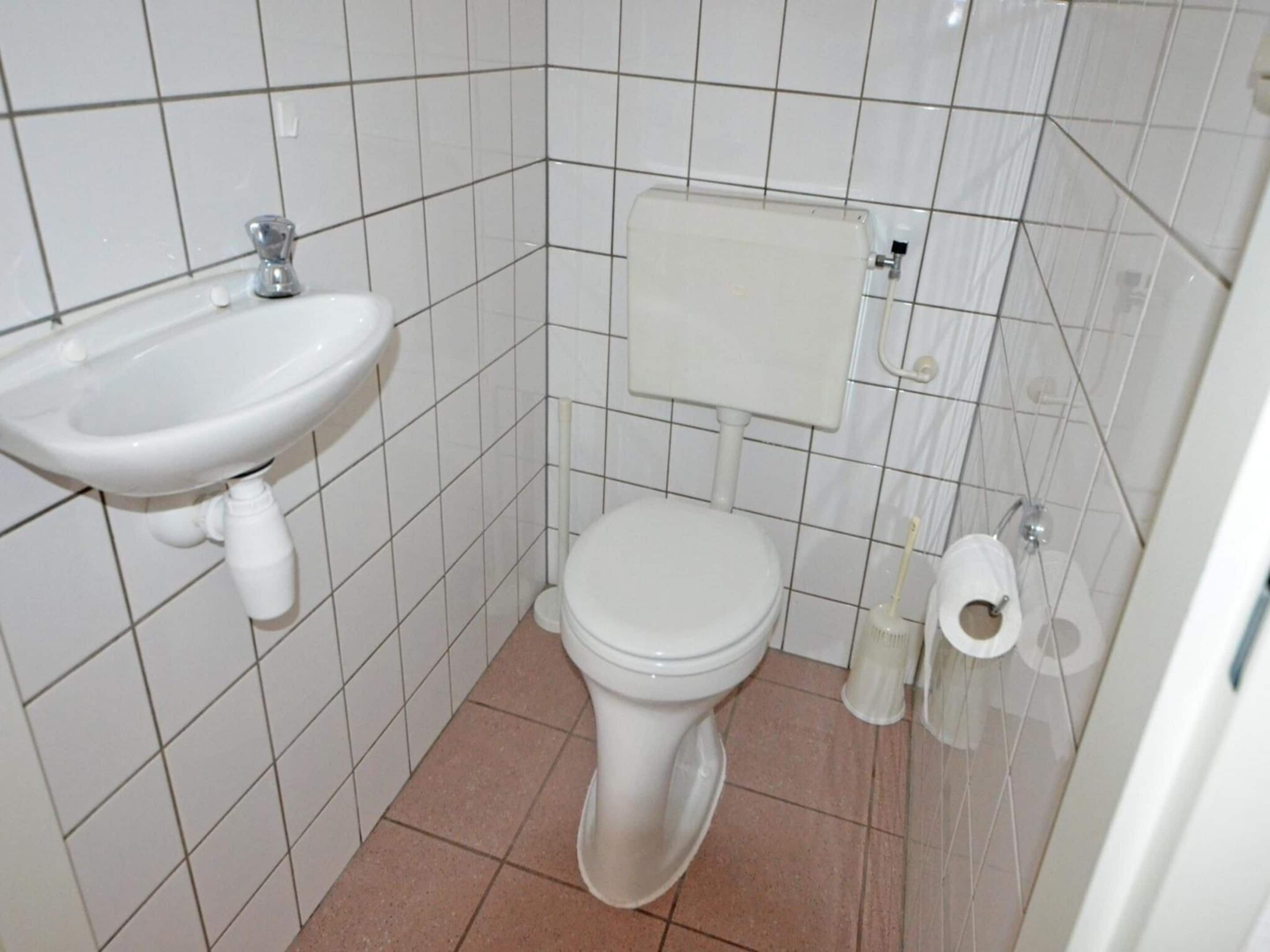 A small bathroom with a white sink, toilet, and bidet.