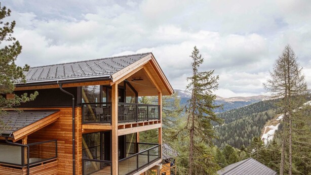 A modern wooden cabin with a balcony, large windows, and a view of a mountainous landscape. - Charming Chalet With hot tub and Sauna (Stadl-Predlitz)