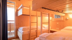 A wooden cabin room with bunk beds, a window, and a small table.