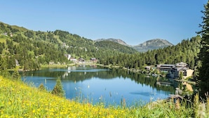 A lake surrounded by lush greenery and buildings with a view of distant mountains.