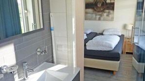 Ένα σύγχρονο μπάνιο με έναν μεγάλο νιπτήρα, έναν καθρέφτη και μια περιοχή με ντους.