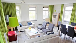 A modern living room with a sofa, armchairs, a coffee table, a dining table with chairs, and a TV stand. - House in Netherlands for 8 With Modern Comfort (Breskens)