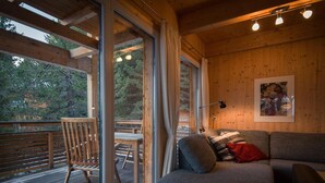 Een gezellig cabin interieur met een bank, een eettafel en stoelen op een houten terras.