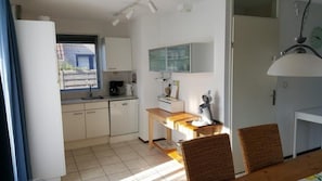 Compact kitchen with dishwasher, sink, coffee maker, and microwave, perfect for quick meals and refreshments.
