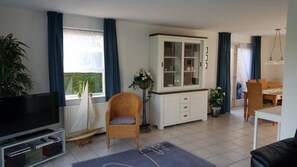 Relax in this stylish living room with a large flat-screen TV, wicker chair, and potted plant.