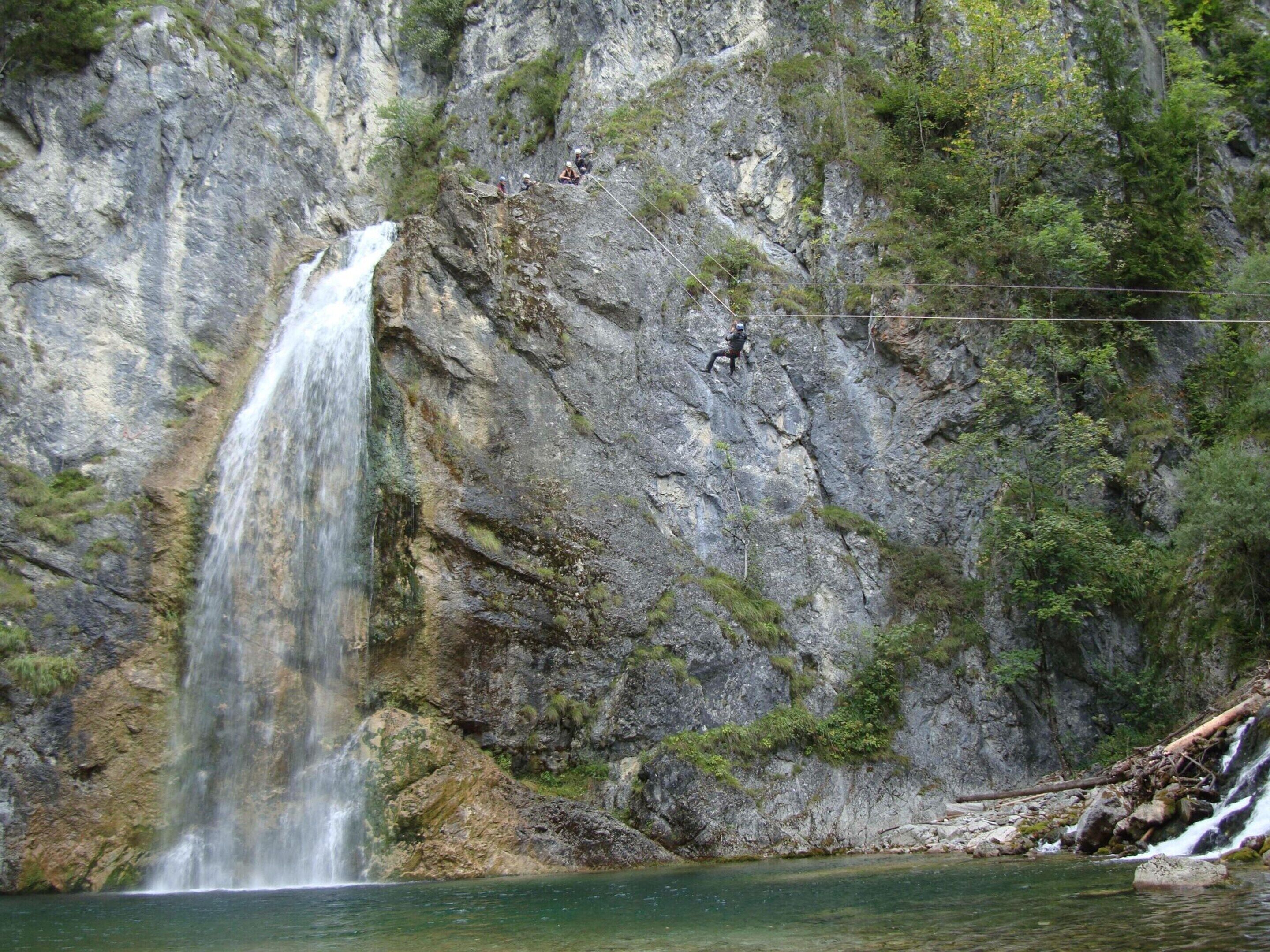 A waterfall cascading down a rocky cliff into a clear pool of water.