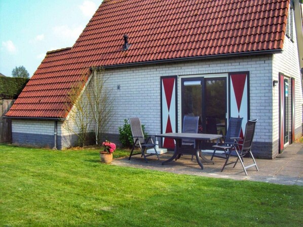 A house with a red-tiled roof, a brick exterior, and a patio with a table and chairs. - Family Retreat in Breskens (Breskens)