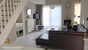 A modern living room with a staircase, a fireplace, and a television. - House in Breskens Near the Beach (Breskens)