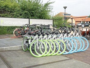 Area parcheggio biciclette con diverse biciclette e un cartello sullo sfondo.
