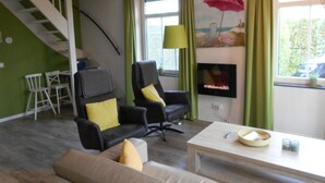 A living room with a staircase, two armchairs, a sofa, a coffee table, and a fireplace. - Holiday Home Breskens Near the Coast (Breskens)