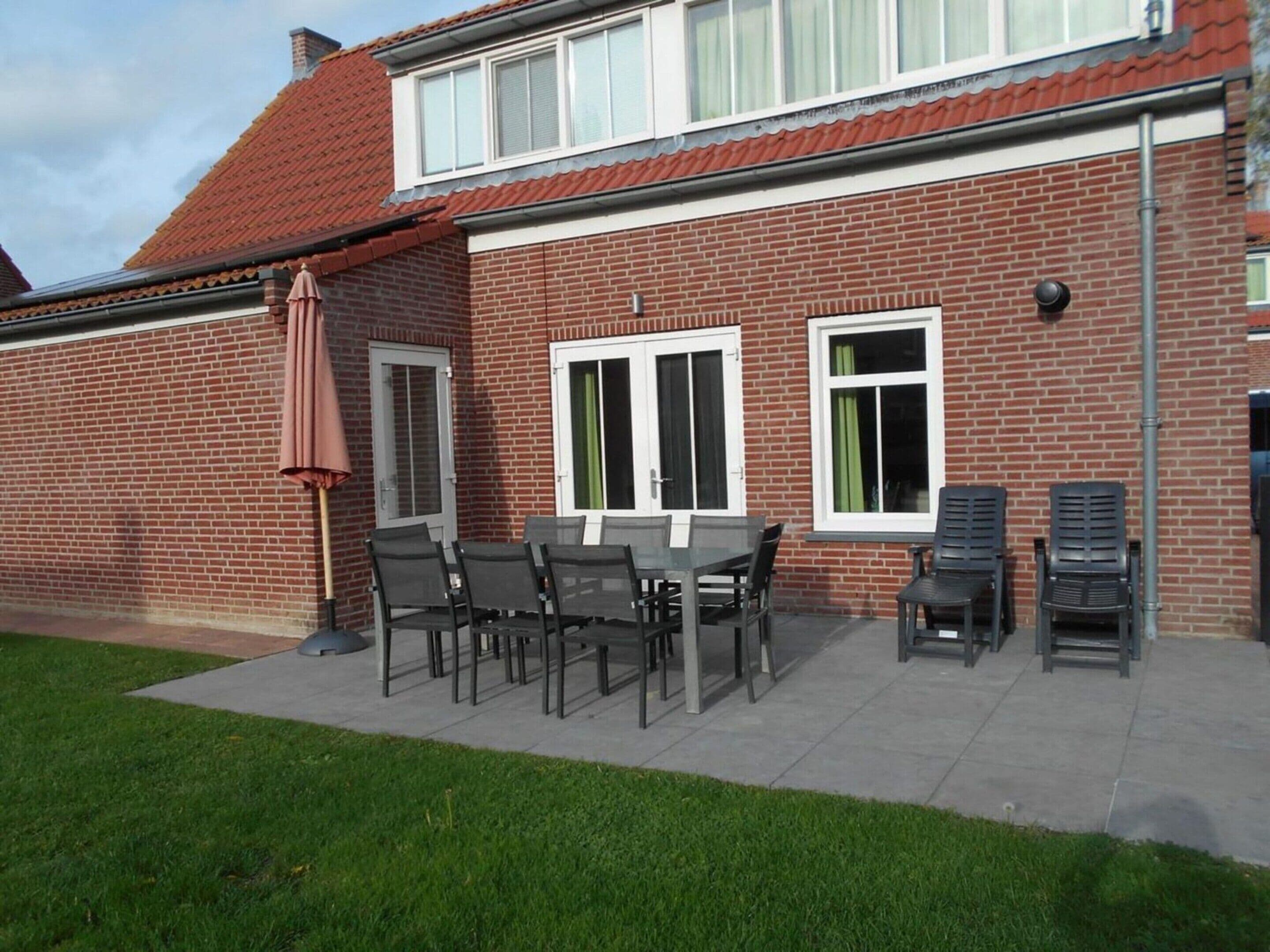 A brick house with a patio, a table with chairs, and a covered area with an umbrella.