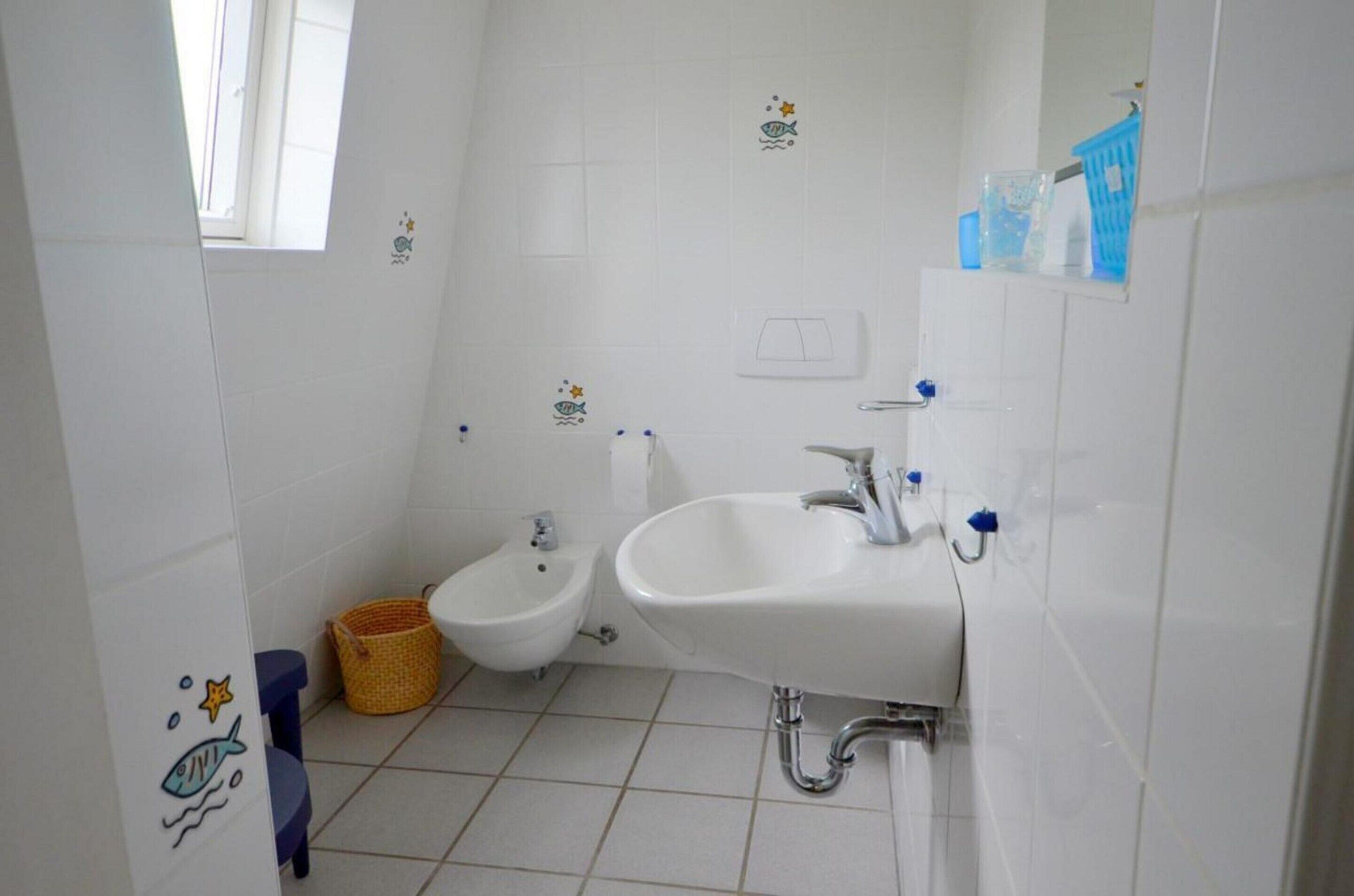 Un baño con bidé, lavamanos y ventana.