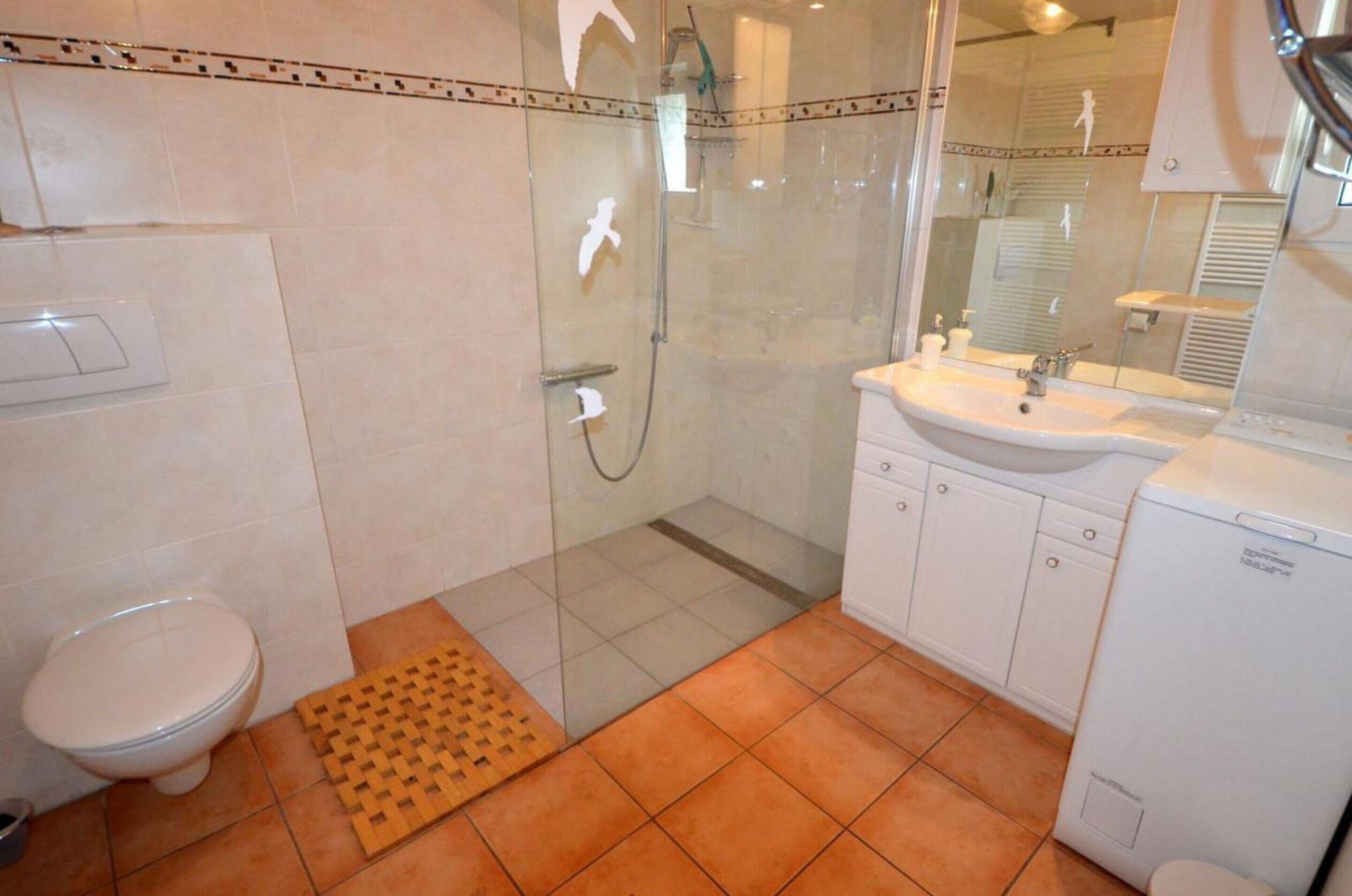 A bathroom with a toilet, shower, sink, and cabinet.