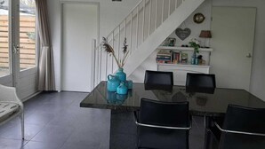 A dining area with a glass table, black chairs, a white staircase, and a white door. - Cozy House in Breskens Near Scenic Beaches (Breskens)