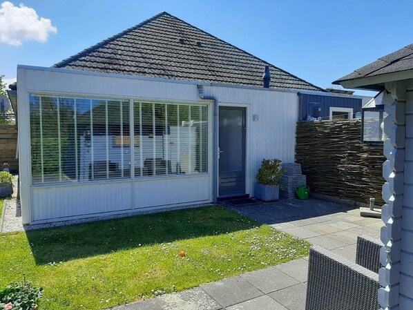 Een modern huis met een groot raam, een deur en een kleine tuin.