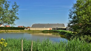 A large building with a flat roof, surrounded by a body of water and greenery. - Lively Bungalow on the Water (Breskens)