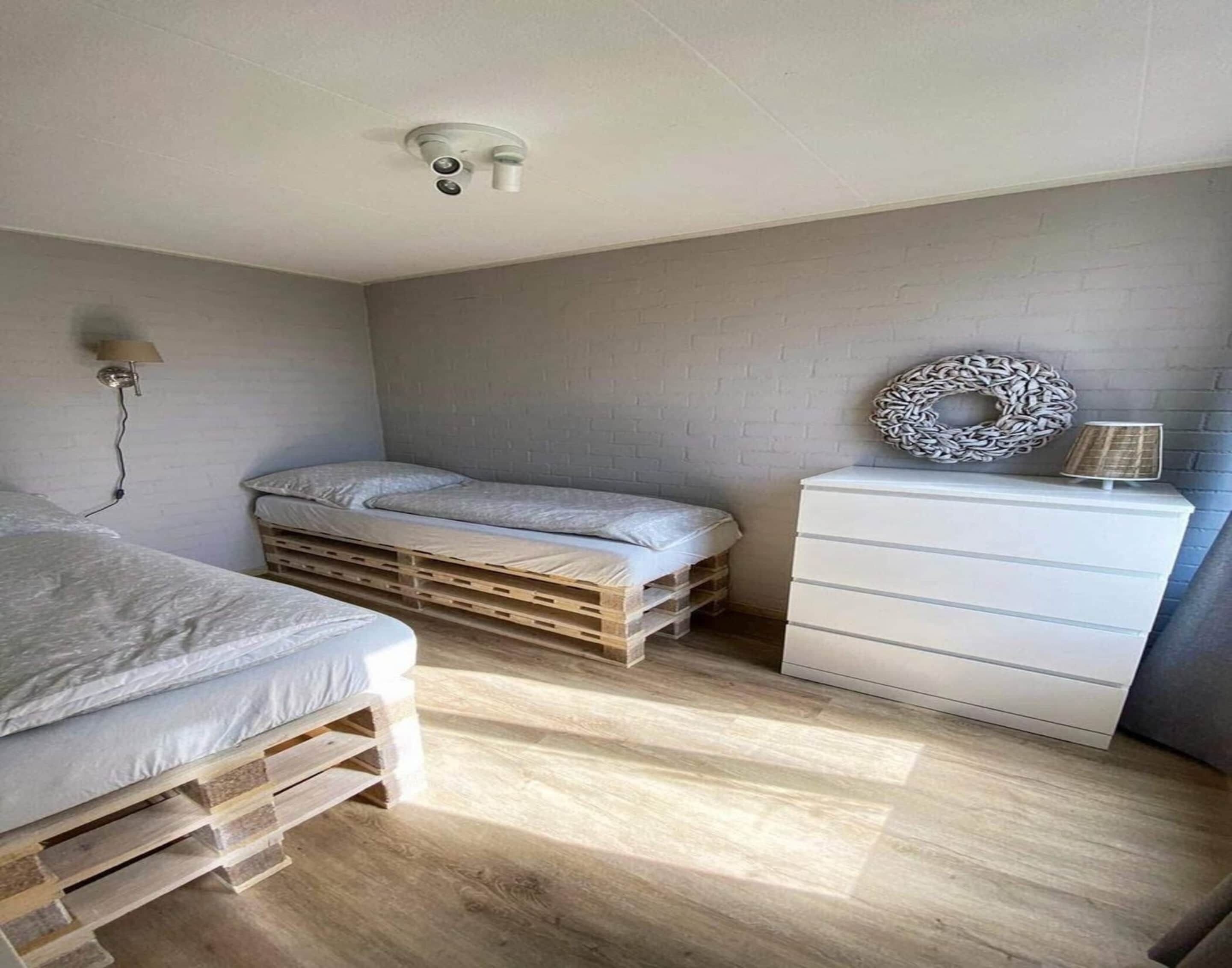 Un dormitorio con cama, cómoda, lámpara y luz de techo.