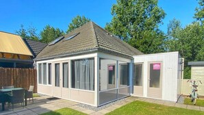 Een huis met een overdekte patio, een omheinde tuin en een fiets.