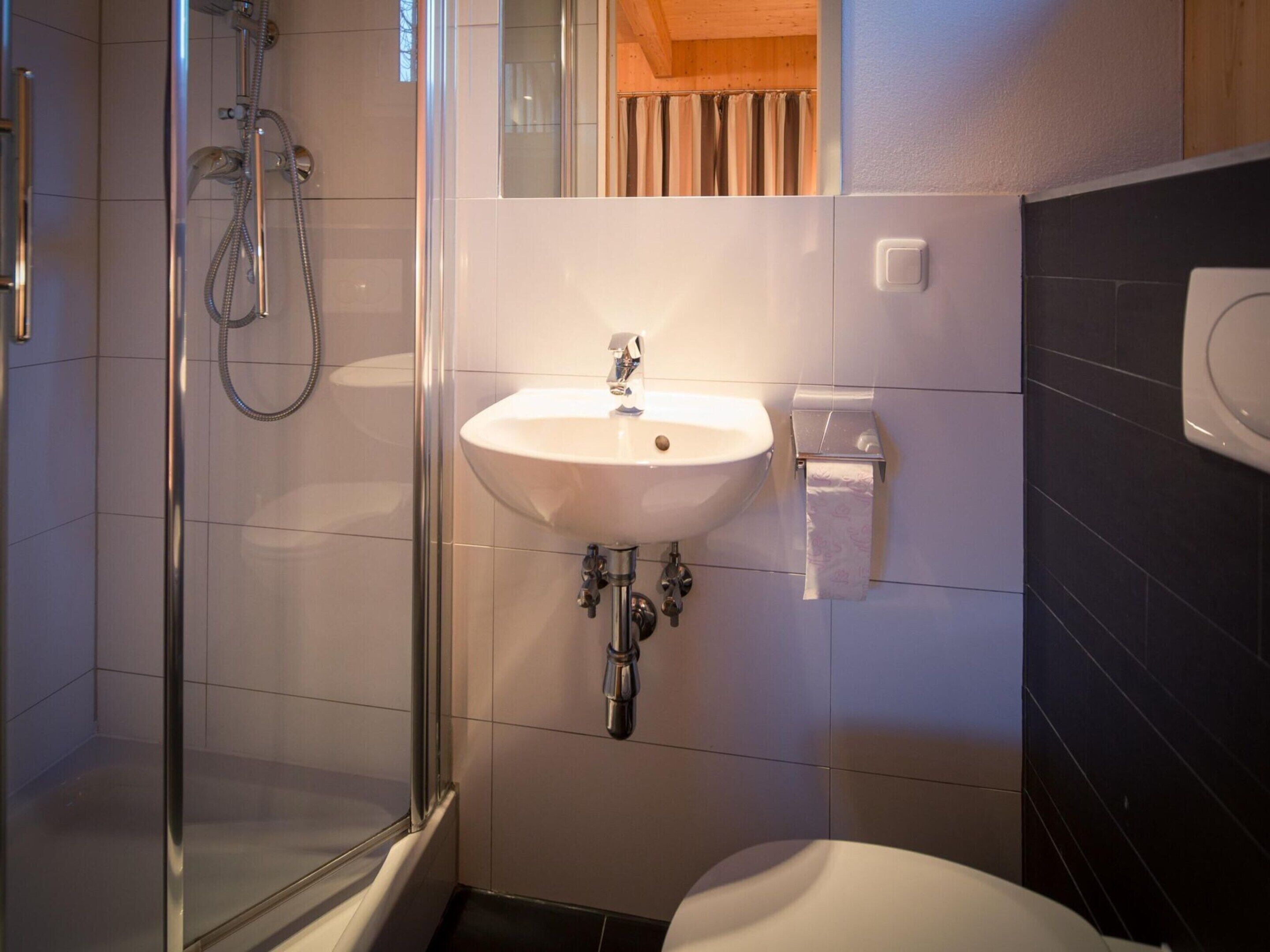 Un baño con ducha de vidrio, un lavamanos blanco y un inodoro.