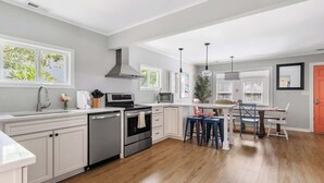 A modern kitchen with white cabinetry, a stainless steel dishwasher, and a central island with stools.
