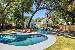 Un jardin avec une piscine, du mobilier d’extérieur et une terrasse en bois.
