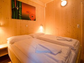 Una habitación con paredes de madera, una cama con sábanas blancas y un cuadro de flores.