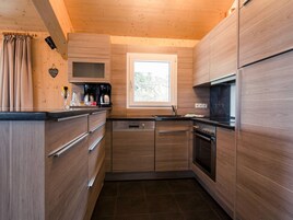 Una cocina moderna con armarios de madera, microondas integrado, estufa y ventana que proporciona luz natural.