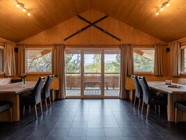 Un comedor con techo de madera, ventanas grandes y vistas a un paisaje boscoso.