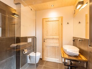 A modern bathroom with a glass shower enclosure, a wooden door, a toilet, and a sink with a wooden countertop. - Attractive Chalet Sauna & Hottub (Stadl-Predlitz)