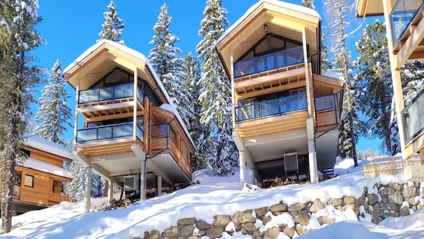 A modern ski resort building with multiple balconies, surrounded by snow-covered trees and a clear blue sky. - Attractive Chalet Sauna & Hottub (Stadl-Predlitz)