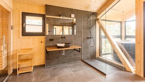 A modern bathroom with a wooden interior, a large mirror, a black sink, and a shower. - Attractive Chalet Sauna & Hottub (Stadl-Predlitz)